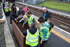  Children & adults planting flowers in a raised bed made with recycled wood